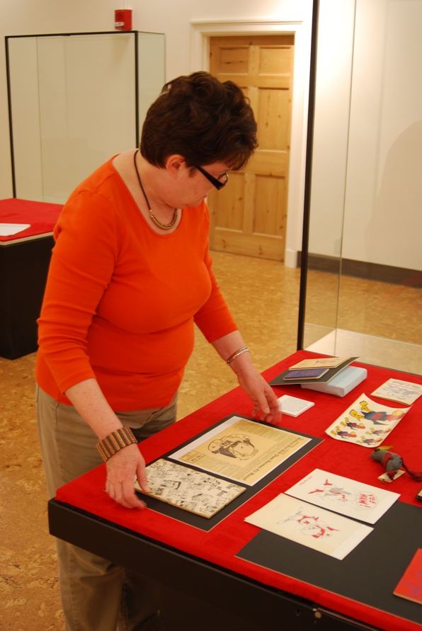 Photograph of University Archivist Becky Schulte positioning an item on mat board within the case