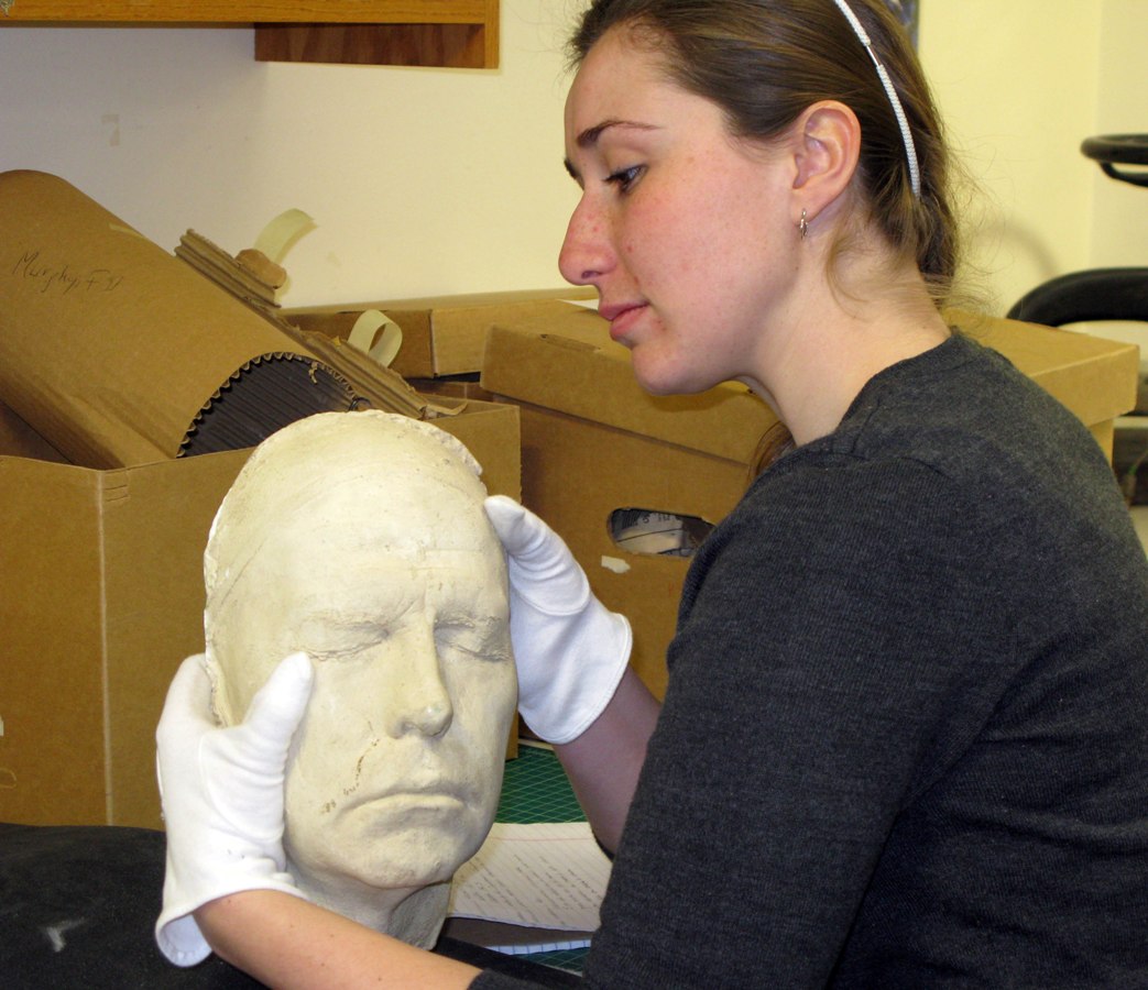 Photograph of Jami Roskamp examining a plaster mask