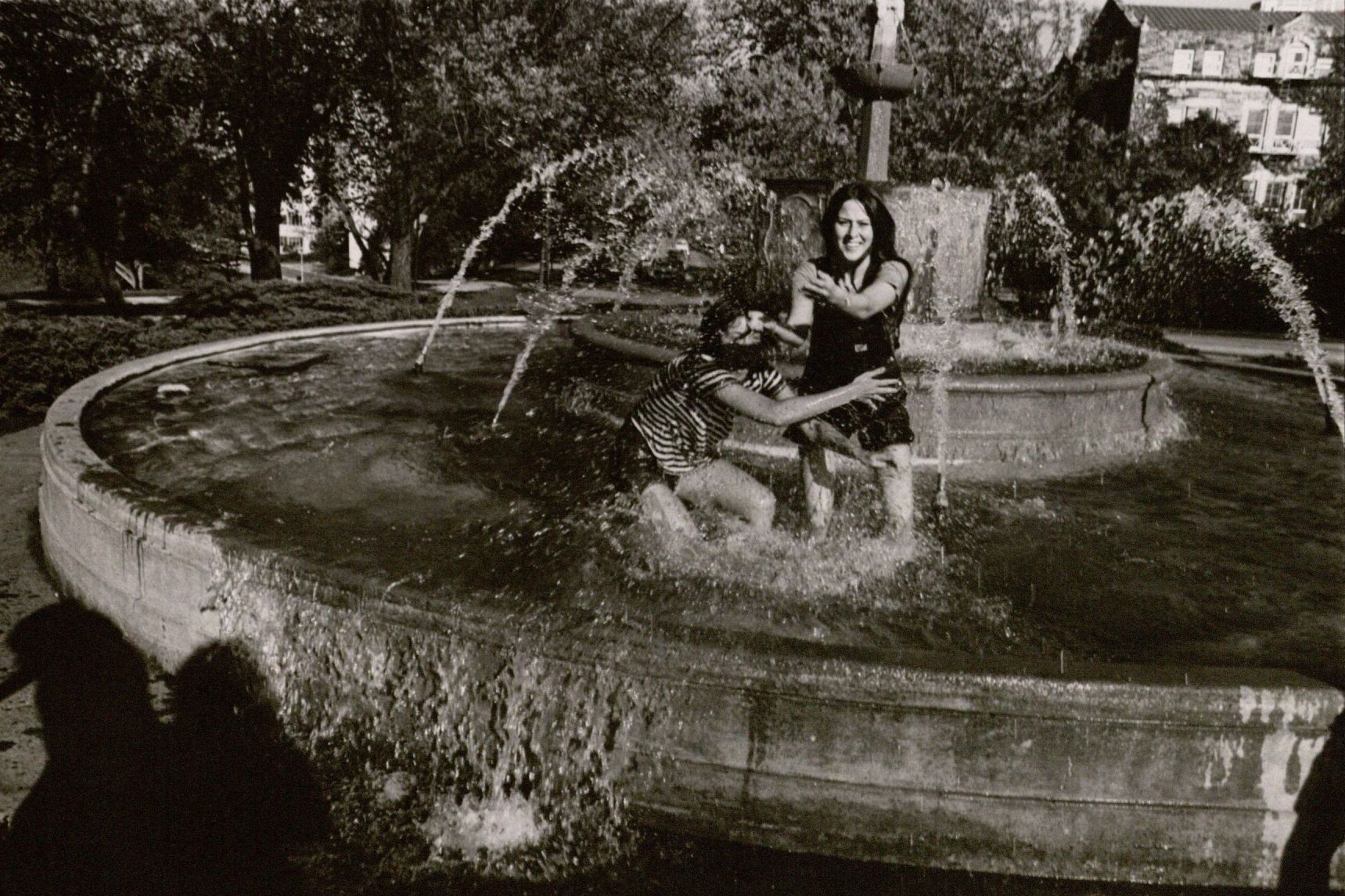 Photograph of two women playing in the water of the Chi Omega Fountain, 1970s