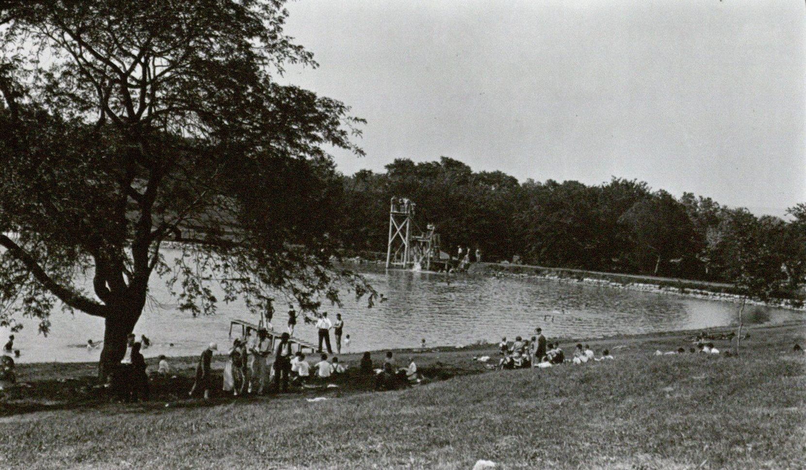 Photograph of swimmers, diving platforms, and sunbathers at Potter Lake, ca. 1926