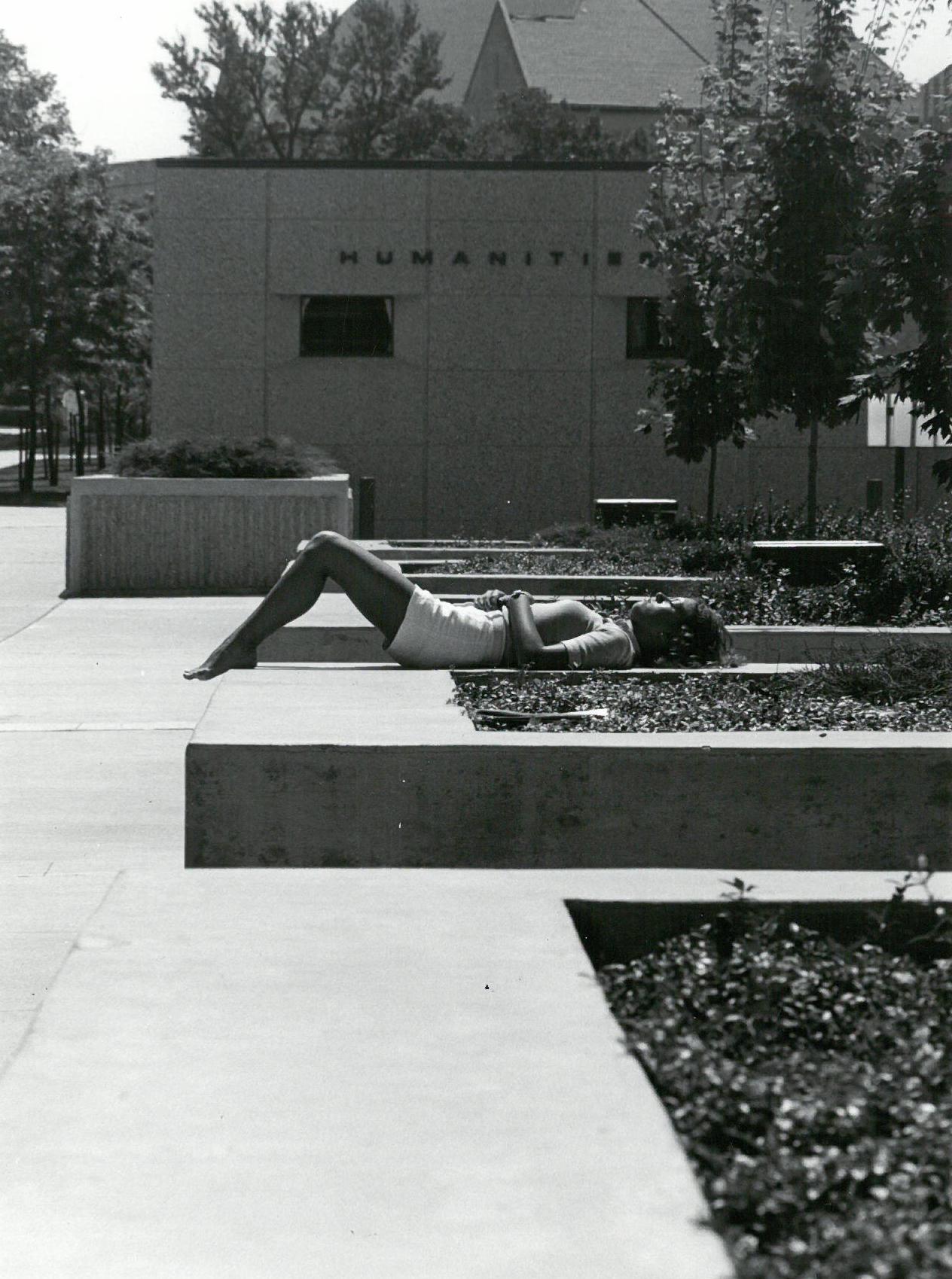 Photograph of student sunbathing at the "Wescoe Beach" in front of Wescoe Hall, ca. 1980/1981.