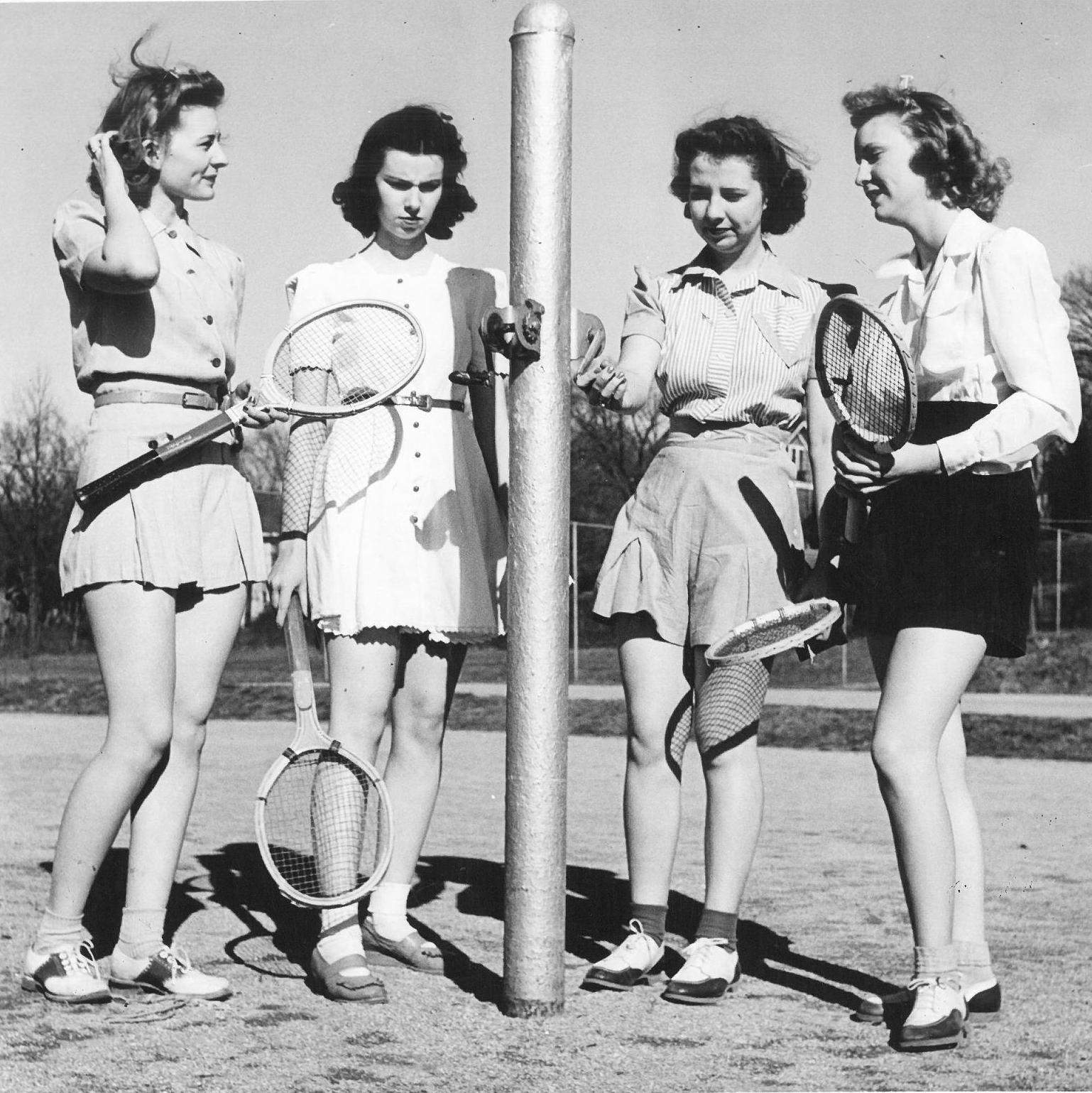 Photograph of four women with rackets preparing to play tennis or badminton, 1940s