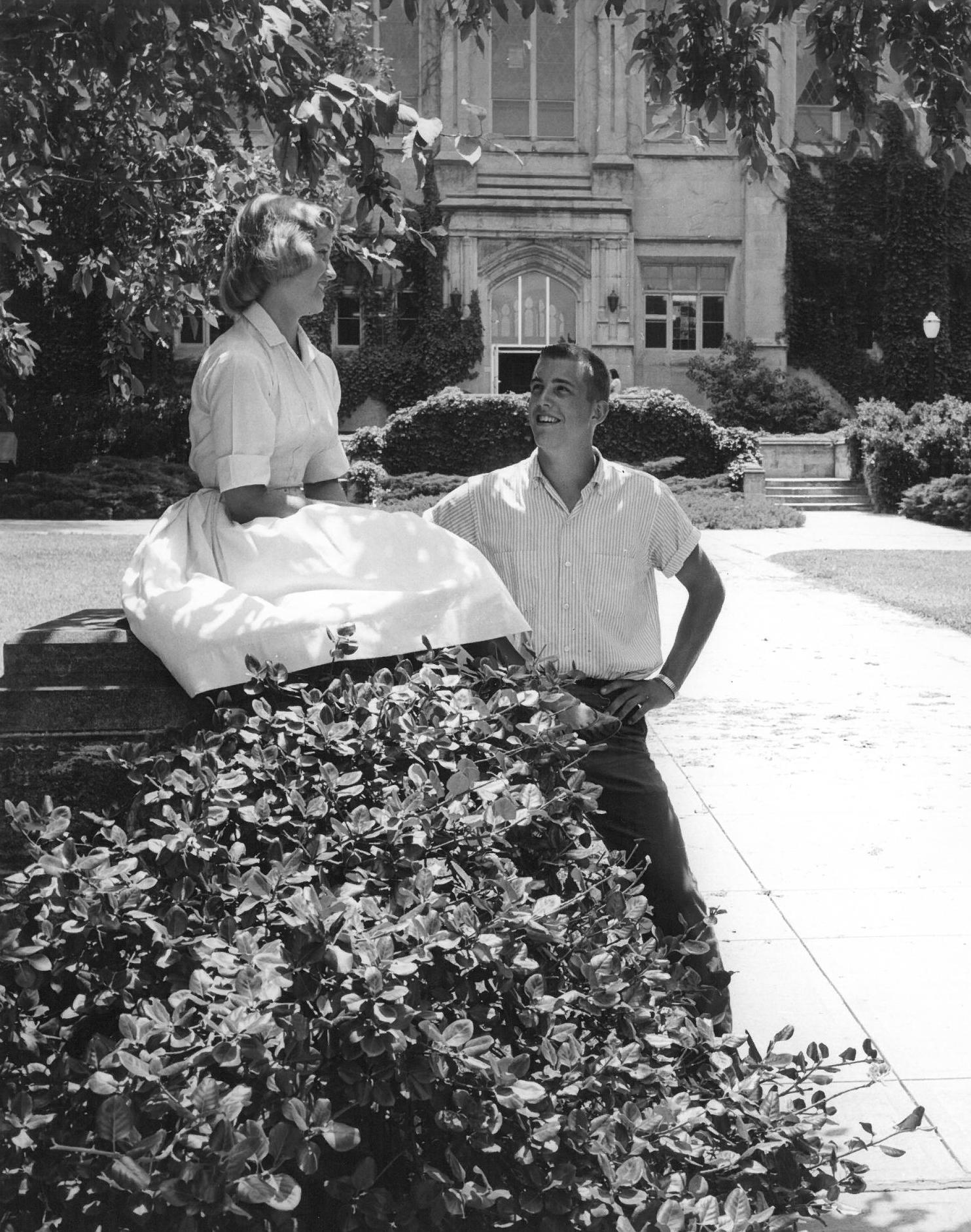 Photograph of a man and a woman chatting in front of Watson Library, 1950