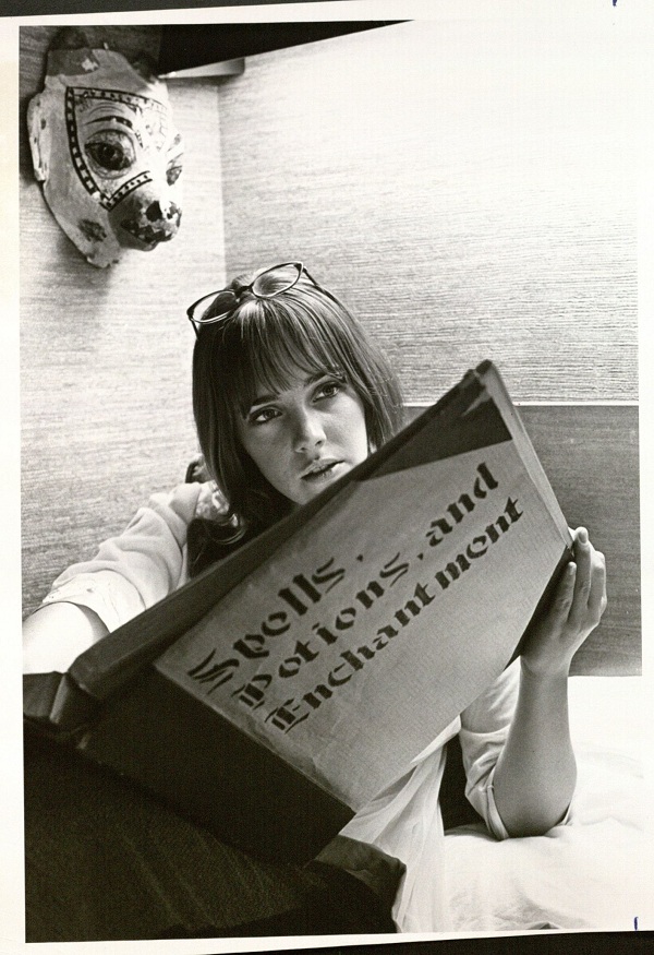 Photograph of a  female KU student reading about spells, potions, and enchantments, 1970