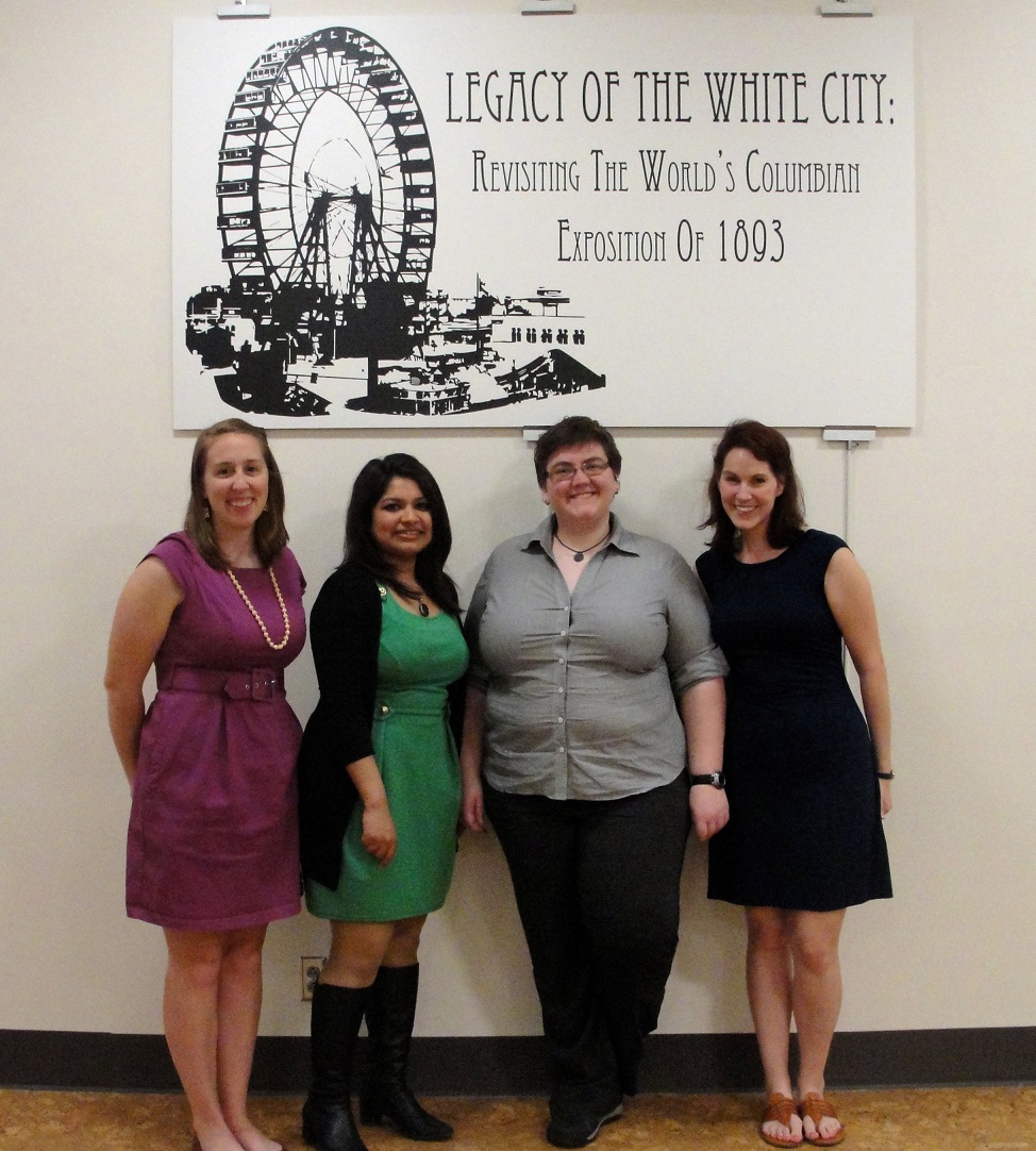 Image of the four exhibition curators in front of the exhibition sign