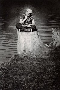 Photograph of a student studying on a stump, 1975-1976. 