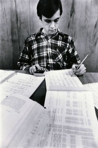 Photograph of student studying with calculator and printouts, 1979-1980.