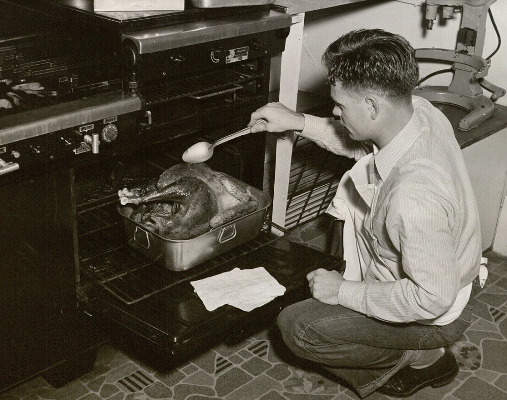 Photograph of a scholarship hall student basting a turkey, 1958