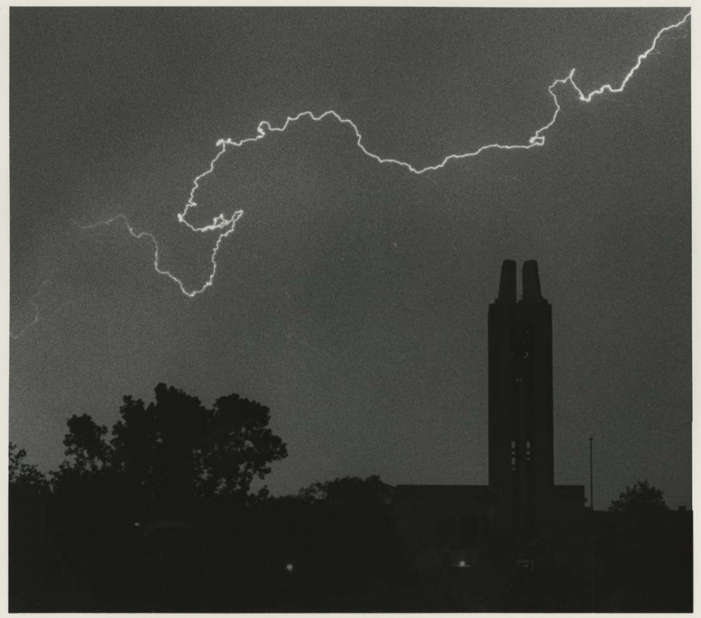 Photograph of lightning flashing above the Campanile and Spencer Research Library, 1980