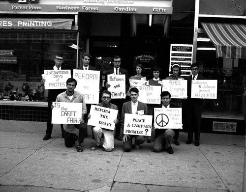 Photograph of Vietnam protestors with signs in front of a store on Massachusetts Street, 1965