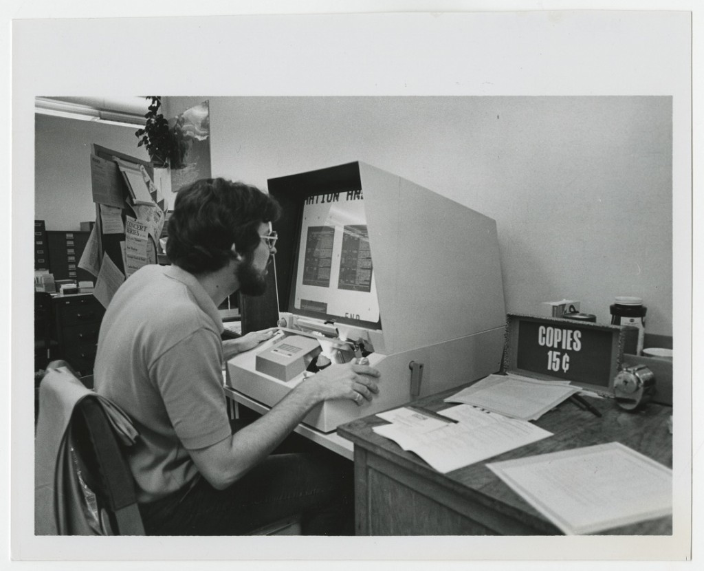 Photograph of a researcher using a microfiche reader, 1970s