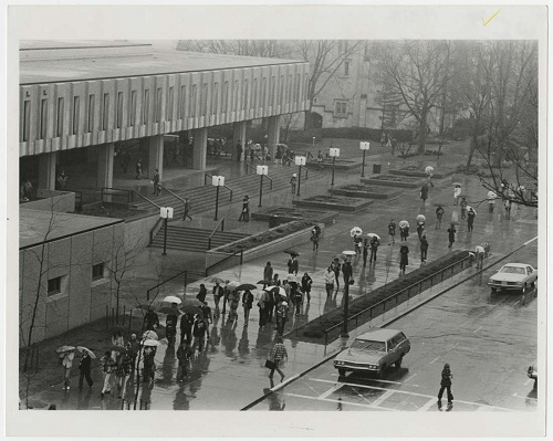 Photograph of students walking in rain in front of Wescoe Hall, 1975-1976