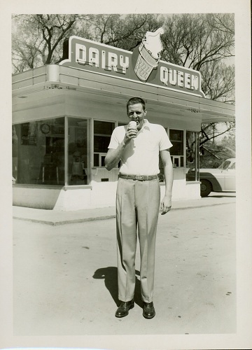 Photograph of Clyde Lovellette stands in front of a Dairy Queen eating an ice cream cone, 1952