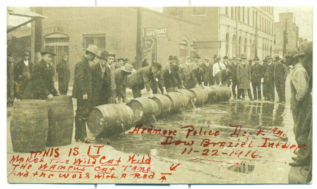 Photograph of Ardmore [Oklahoma] Police Department members pouring out barrels of alcohol, November 22, 1916