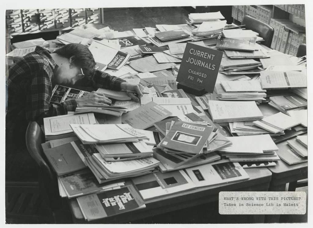 Photograph of a student asleep on a pile of journals in library, 1978