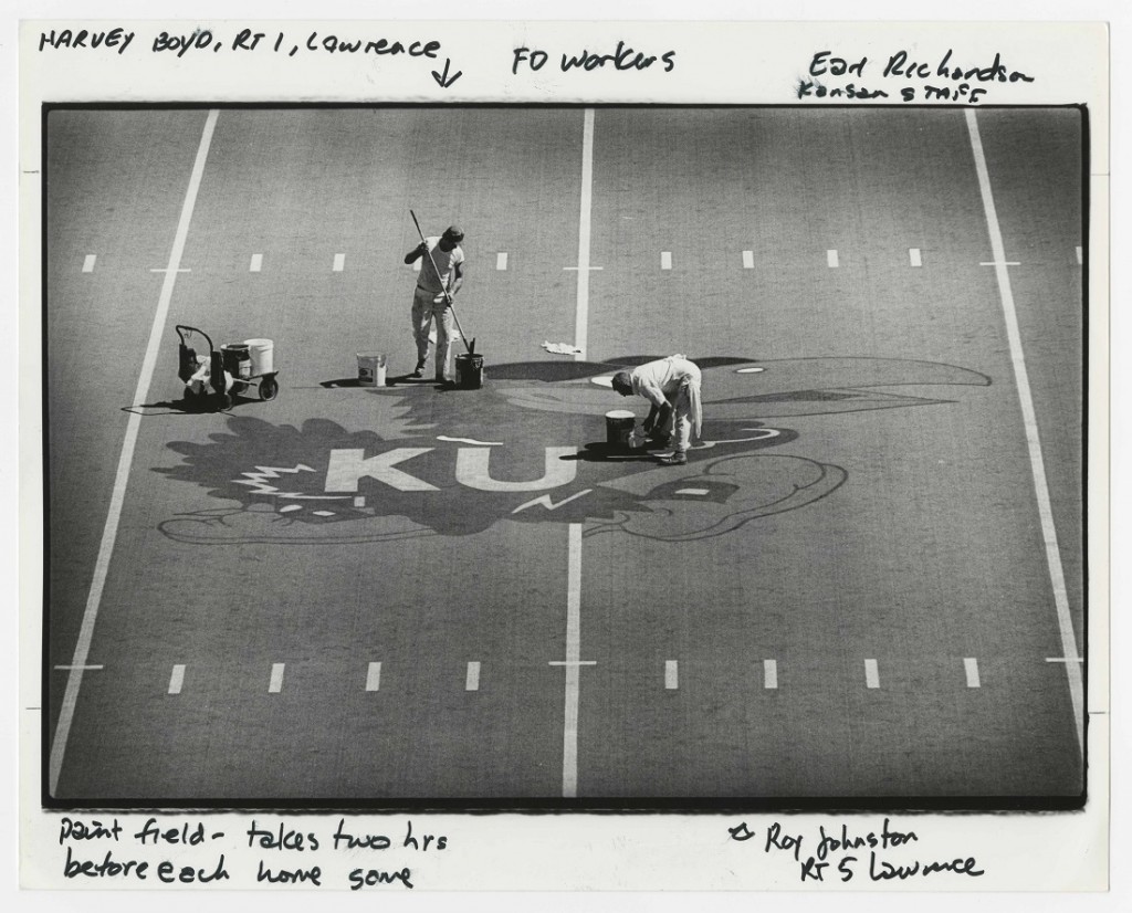 Photograph of Facilities workers painting a Jayhawk on the field at Memorial Stadium, 1980s