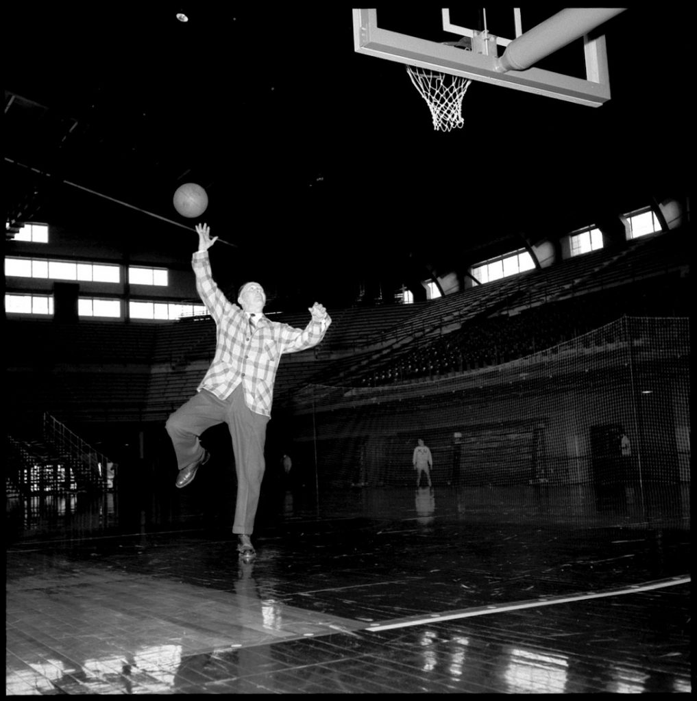 Photograph of Phog Allen shooting a layup in Allen Fieldhouse, 1955