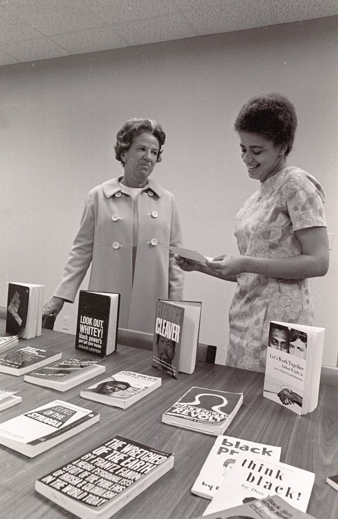 Photograph of Elizabeth Snyder and Betty Ann Bush examining Bush's book collection at the Snyder Book Collecting Contest, 1969