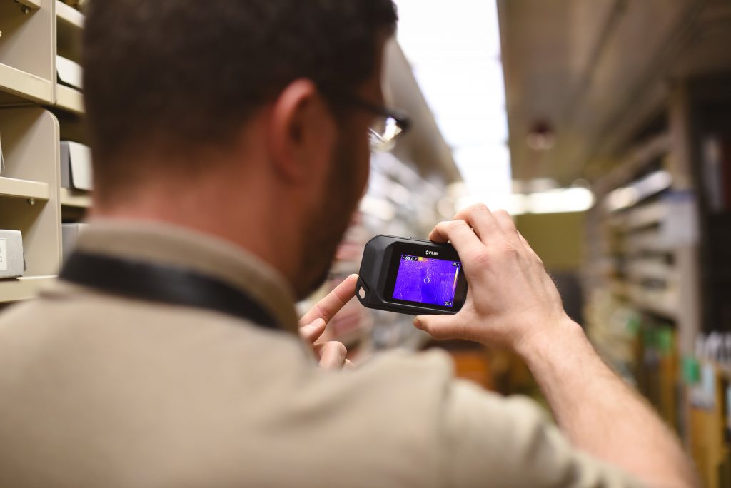 Consultant using an infrared camera in the Spencer Library stacks, University of Kansas Libraries.