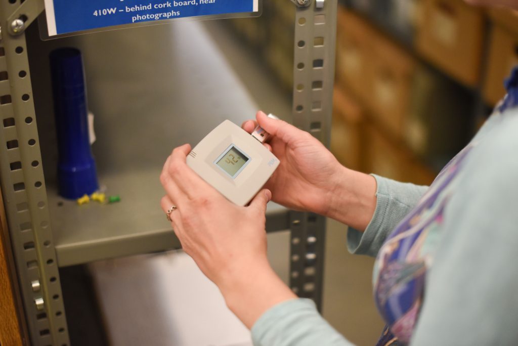 Consultant using a datalogger in the Spencer Library stacks, University of Kansas Libraries.