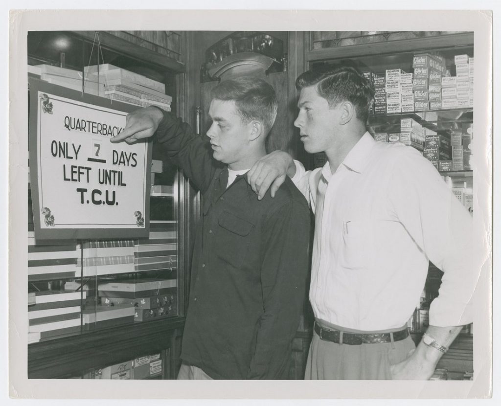 Photograph of two KU football players looking at a sign, 1951