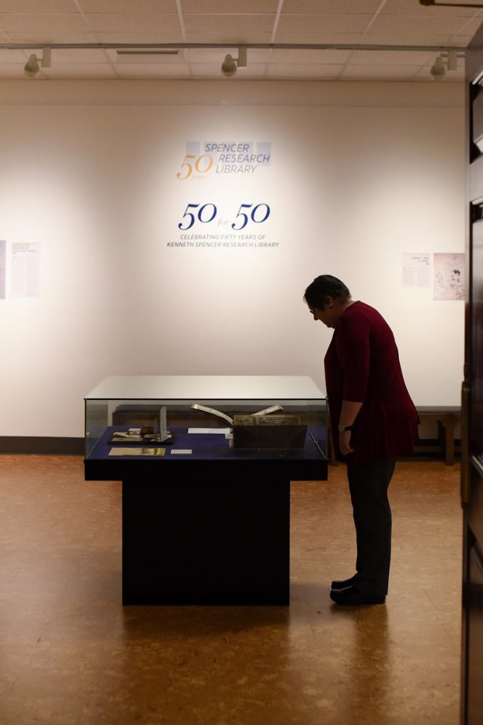 Photograph of a guest exploring the "50 for 50" exhibit at Spencer Research Library's fiftieth anniversary celebration, 2018