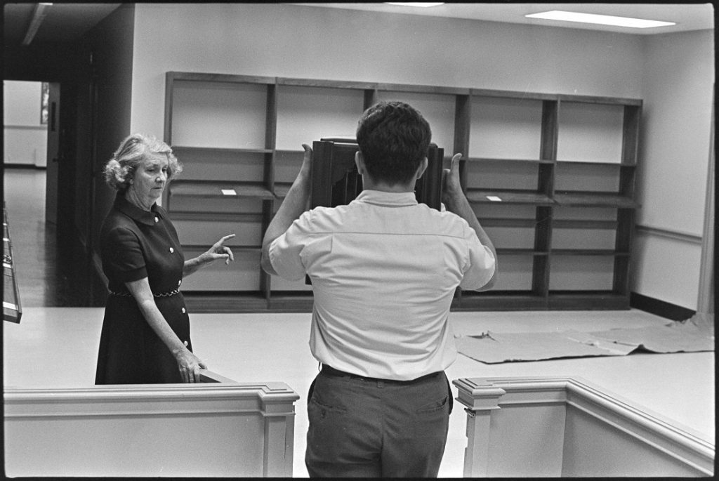 Photograph of Helen Spencer directing the placement of furniture at Kenneth Spencer Research Library, 1968