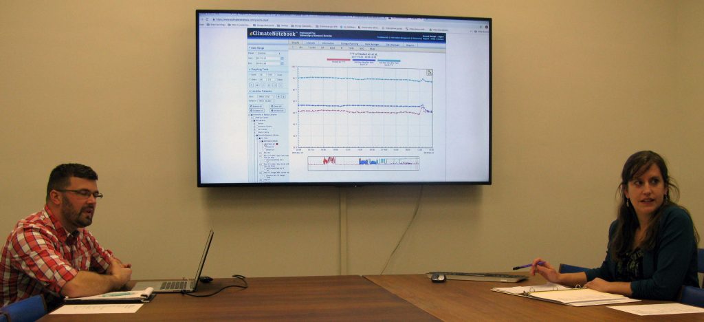 Consultants discussing temperature and relative humidity graphs from Spencer Research Library