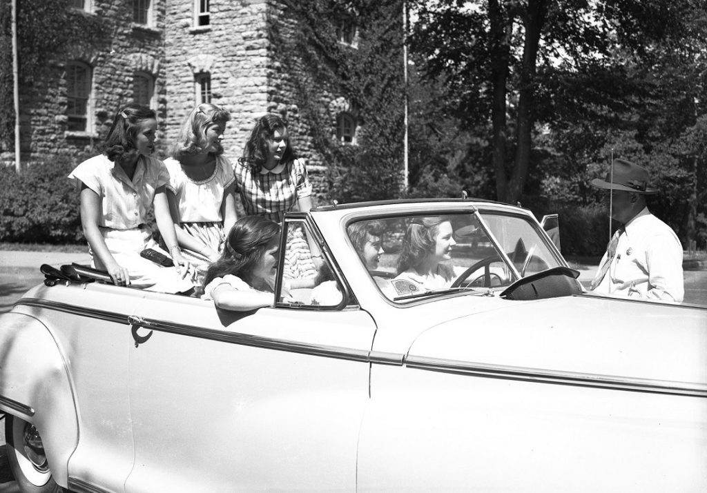 Photograph of women students in a car talking to an officer, 1940-1949