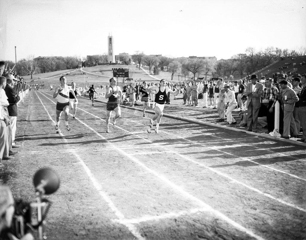 Photograph of athletes finishing a race at the Kansas Relays, 1956