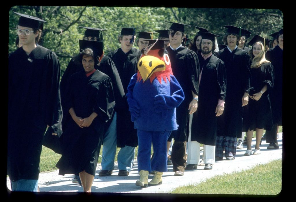 Photograph of KU students and Baby Jay walking down the hill at Commencement, 1974