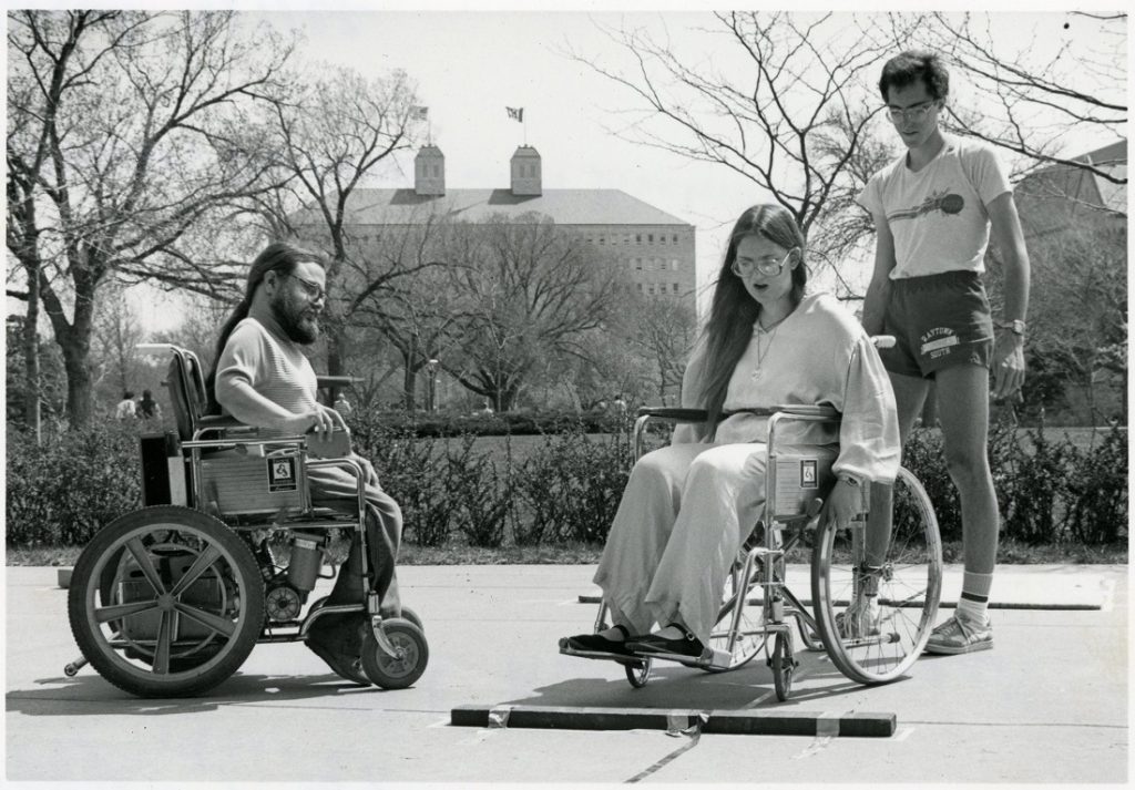 Photograph of members of Students Concerned with Disabilities in front of Fraser Hall during Disabled Awareness Week, 1982