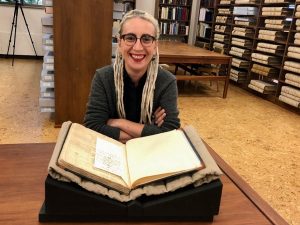 Photograph of N. Kivilcim Yavuz in the Kenneth Spencer Research Library's Reading Room with MS E71 (a manuscript copy of Vergil's Aeneid, Italy, circa the early 1400s)