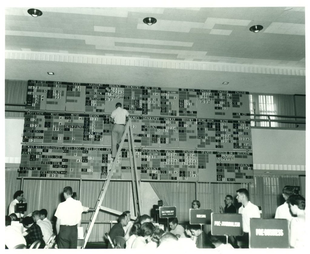 Photograph of someone updating the "enrollment bullpen," 1955