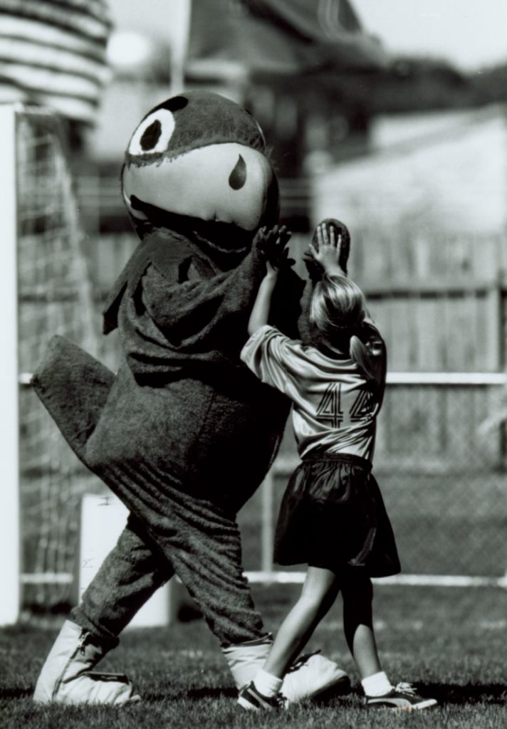 Photograph of Baby Jay high-fiving a young soccer play, 1996