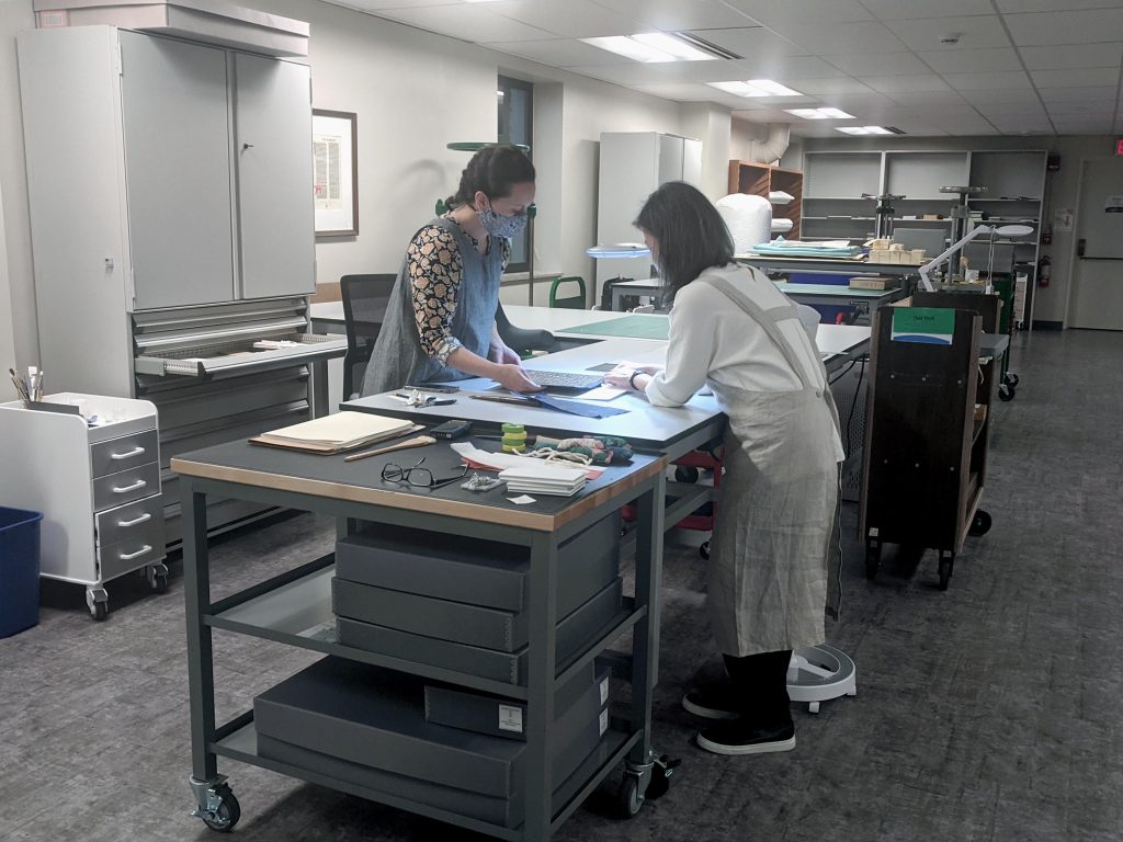 Mellon Initiative conservator Jacinta Johnson and visiting conservator Minah Song examine a rare Korean sutra from Spencer's collection.