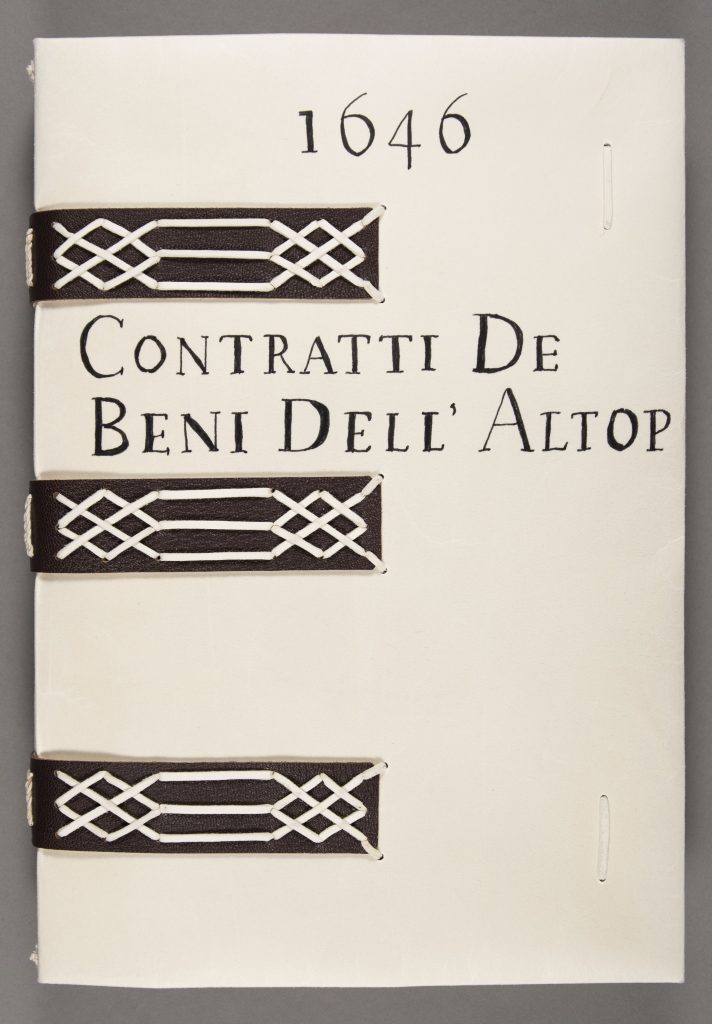 Model of a book in Spencer Library's collection, featuring a parchment cover with leather bands. Title and date are hand-written on the top cover.
