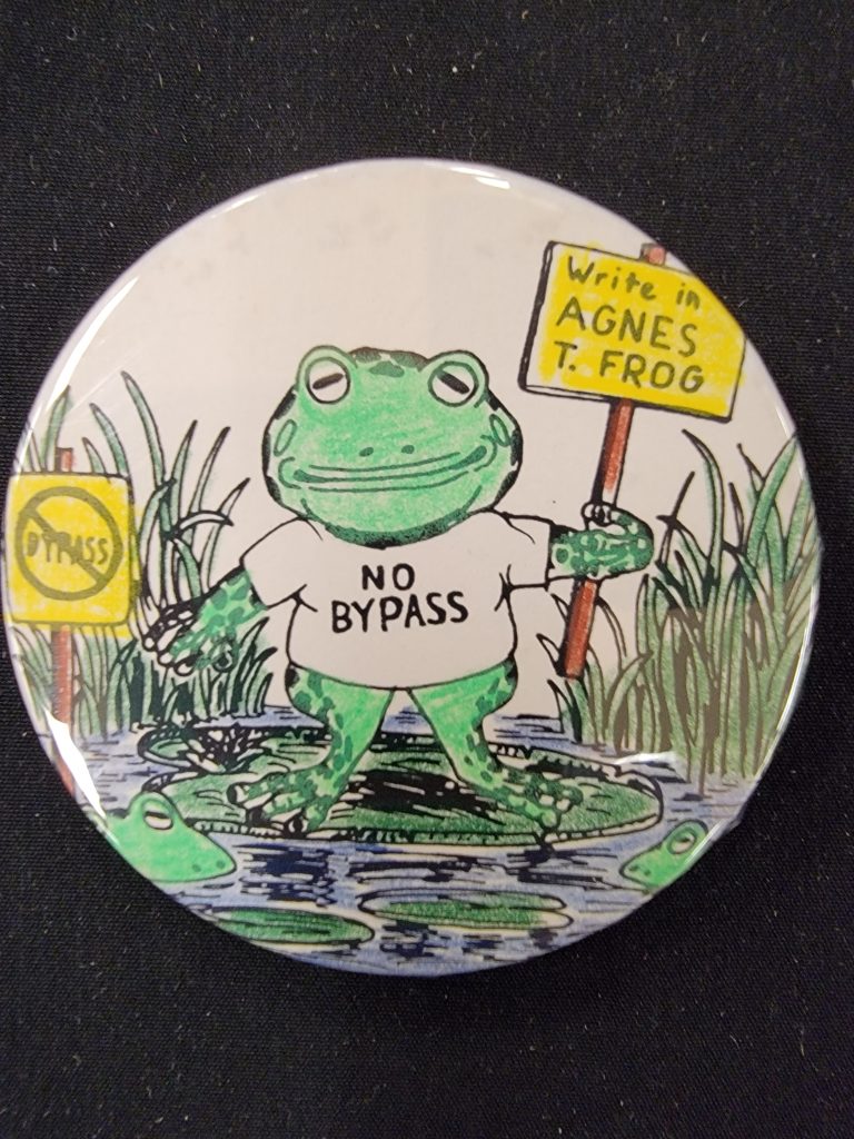 Button with drawing of a frog wearing a "No Bypass" shirt and holding sign saying "Write in Agnes T. Frog".