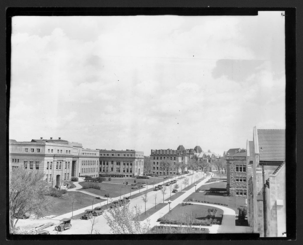 Black-and-white photograph of large buildings on both sides of a wide street.