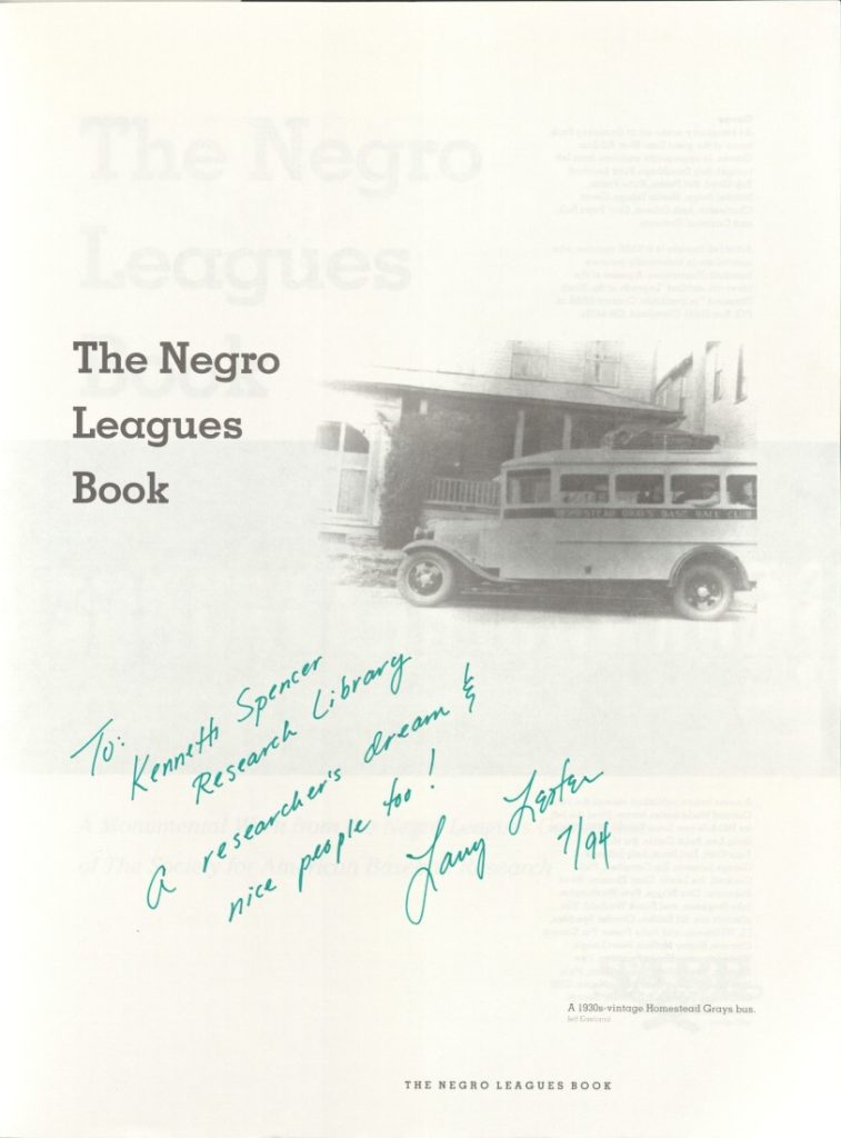 Black-and-white photograph of a Negro Leagues baseball team bus in front of a house. Page signed by author Larry Lester in green ink.