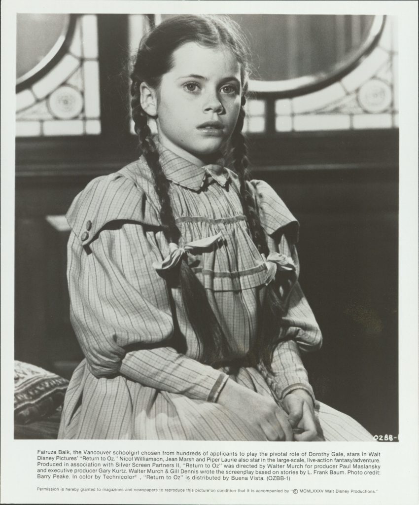A young girl with two braids looking worriedly off into the distance.