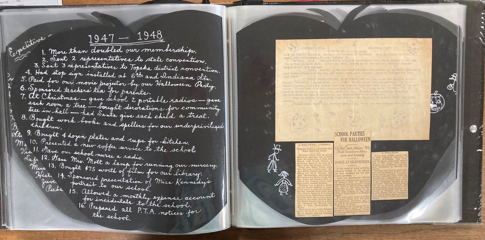 Black pages in the shape of an apple. On the left is white handwritten text detailing highlights from the school year. On the right are clippings.