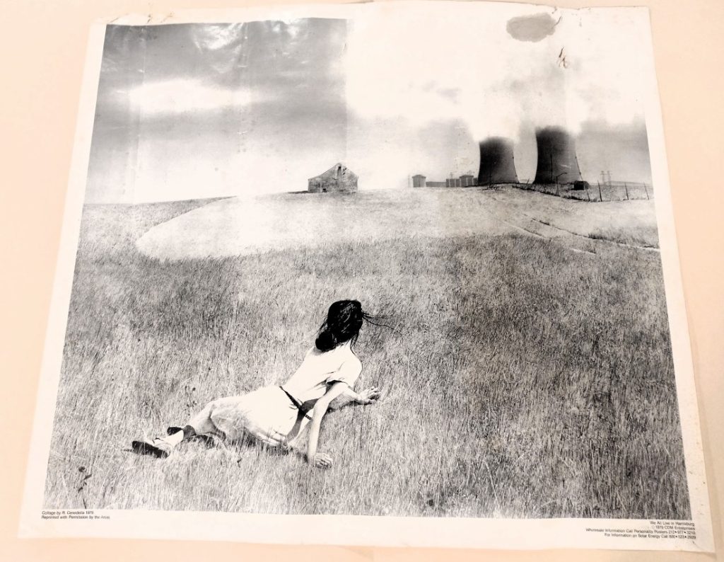 Black-and-white illustration of a woman lying in a field of grass, looking at two nuclear reactors in the distance.