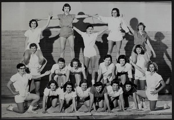 Black-and-white photograph of girls kneeling and standing on each other, with the group forming the shape of a pyramid.