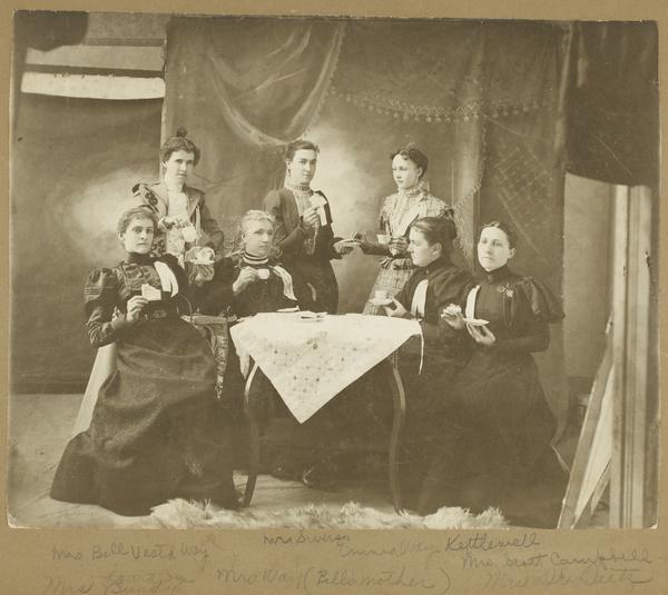 Black-and-white photograph of seven women drinking tea and eating.