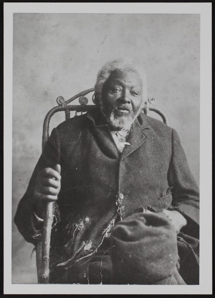 Black-and-white photograph of an older African American man in sitting in a chair.