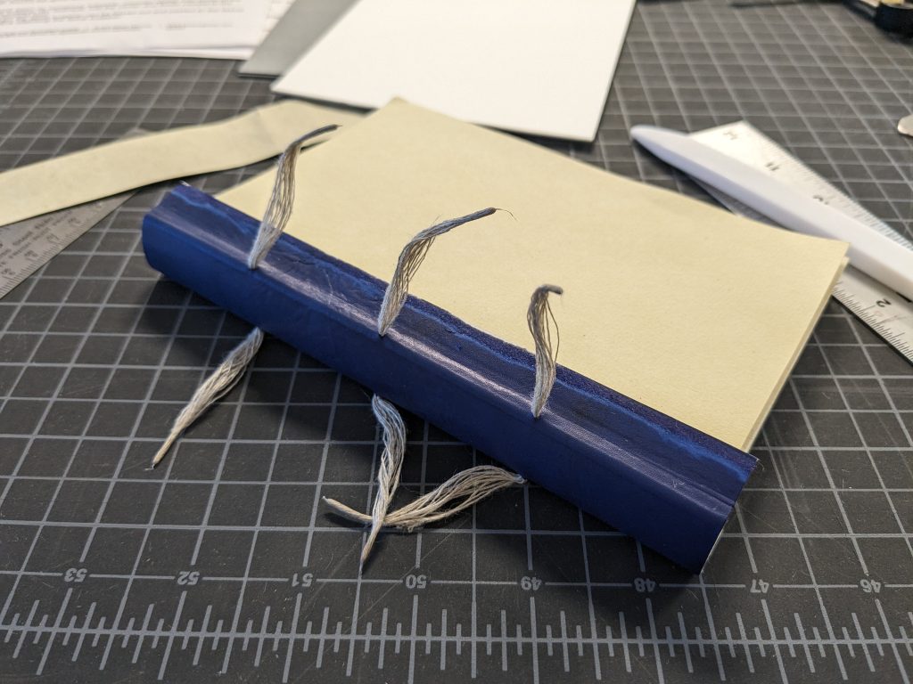 Detail view of the Even More Simplified binding with spine wrapper laced on, before attaching boards.