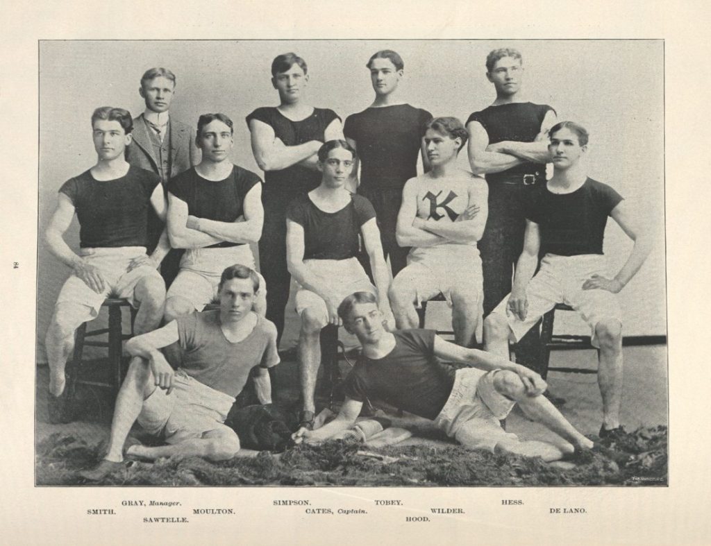 Black-and-white photograph of college men in white shorts and black short-sleeve shirts.