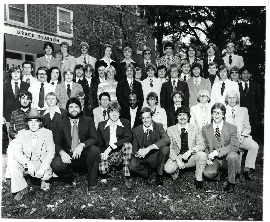 Group of formally-dressed men posing in front of their residence hall.