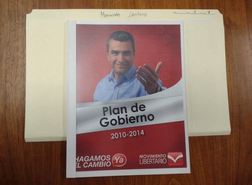 Photograph of a pamphlet by the Movimiento Libertario party titled "Plan de Gobierno 2010-2014." It shows a man stretching out his hand to the reader.